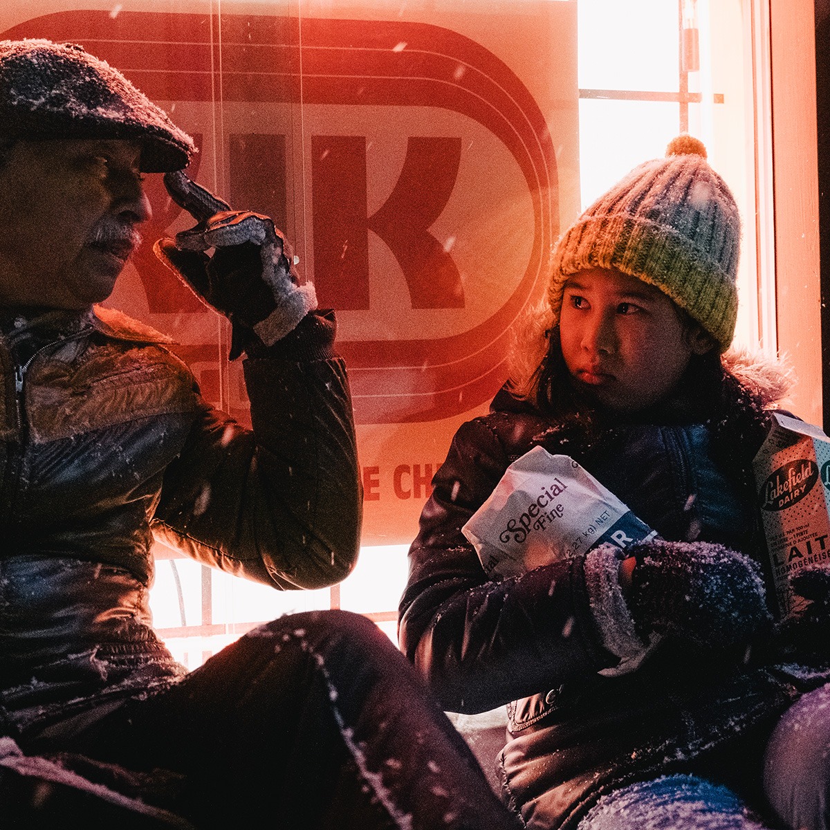 A man and a girl outside a store in the snow.