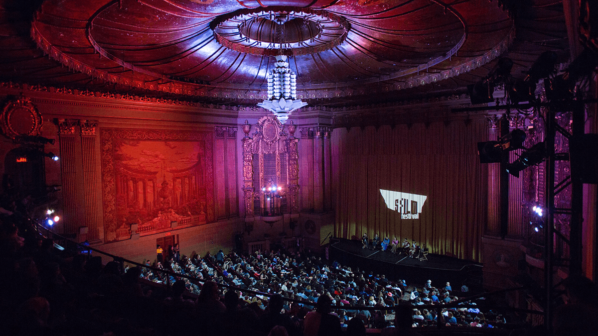 A full Castro Theatre with the SFFILM wordmark projected onto the screen