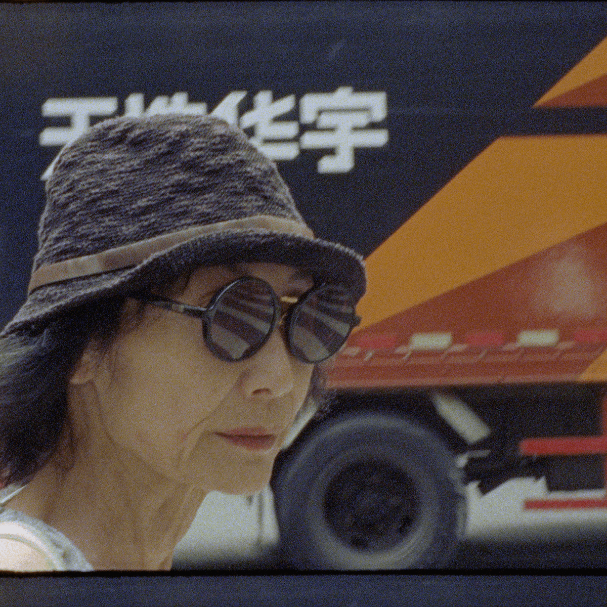 a person with glasses and a hat stands in front of a truck