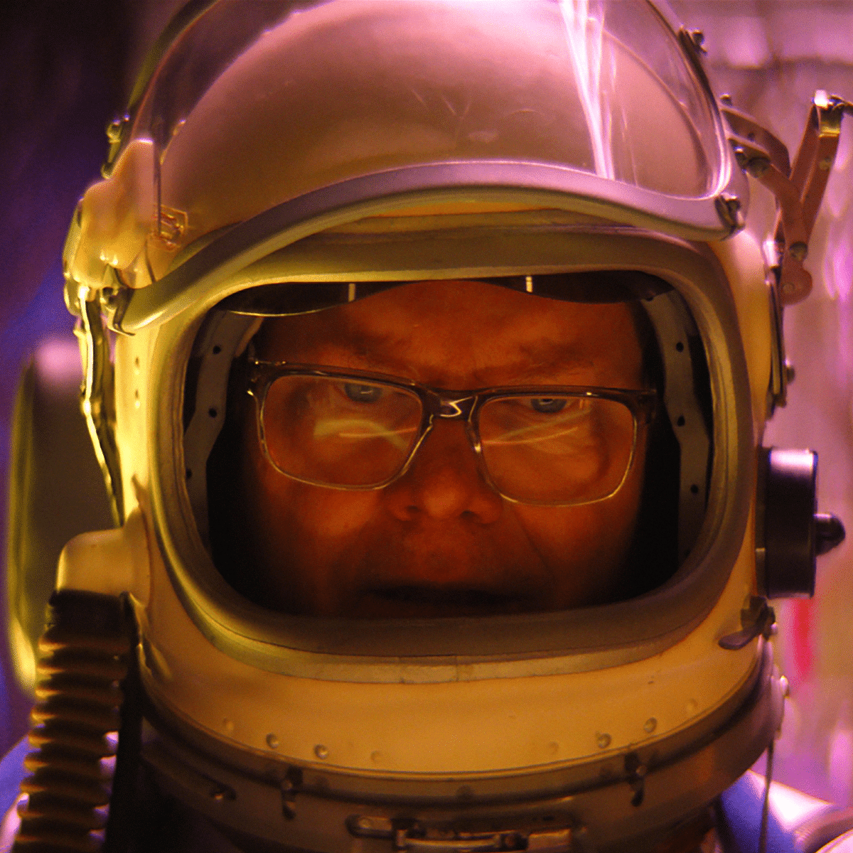 person in a space helmet and glasses looks concerned