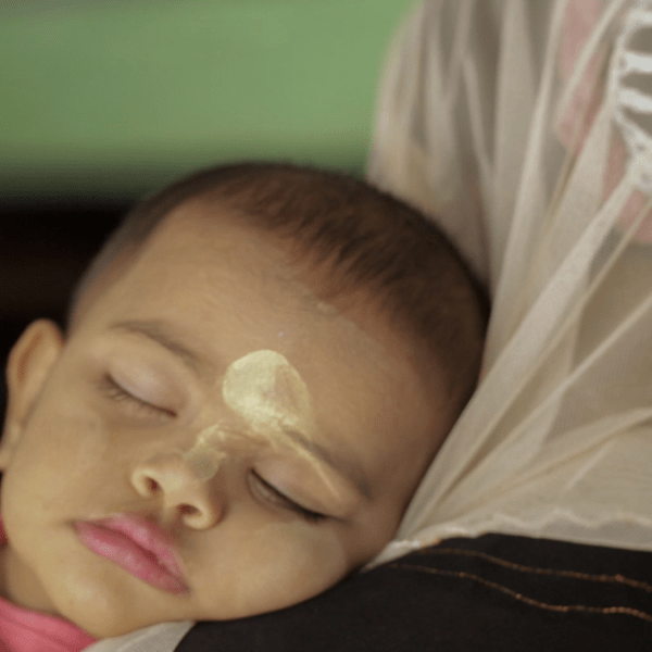 a person rests a sleeping baby on their shoulders