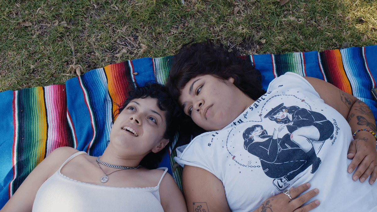 two people lay on a colorful blanket outside
