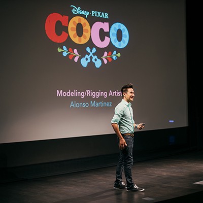 person standing on stage with Coco title screen in background
