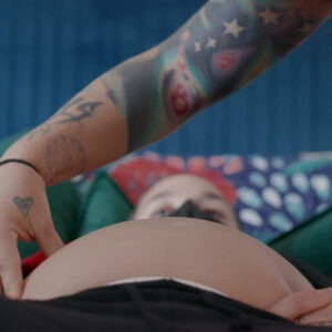 a pregnant woman laying on a bed having their belly checked.