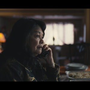 a woman on the phone sitting at their dining table at home.