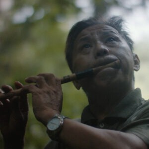 a man playing a flute in the woods.