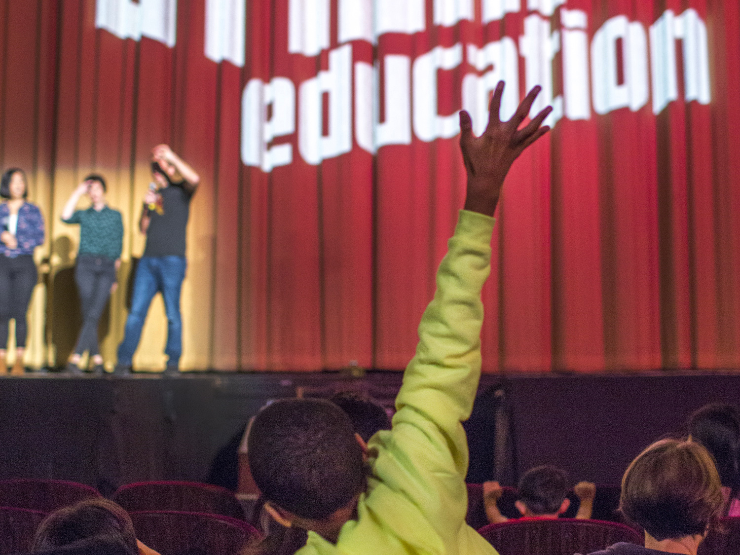 a child raising their hand in the audience.