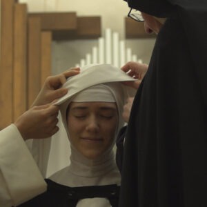 two women is putting a nun's hat on another woman's head.