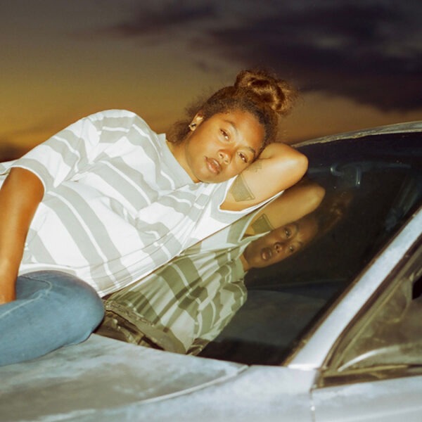a woman sitting on a car hood at sunset.