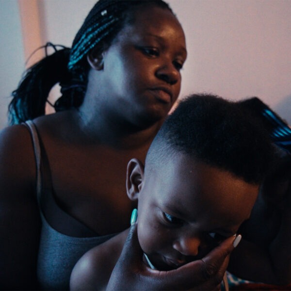 a woman combing a child's hair while sitting on a bed.