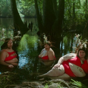 a group of three women wearing red bikinis lounging in a lake.