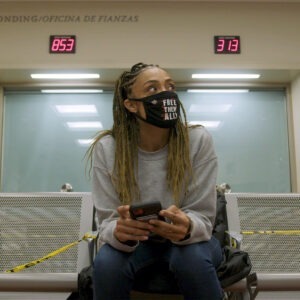 a woman in a face mask sits in a waiting room.