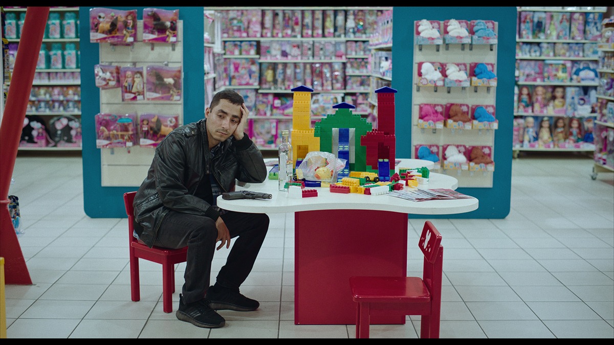a man sits in a toy store with a gun and a lego building.