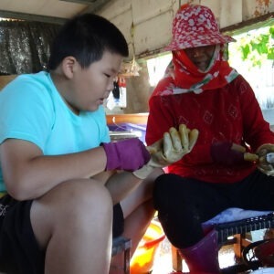 a young boy and a man sit cutting ingredients together.