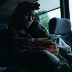 a woman and child sit together sleeping on a bus.