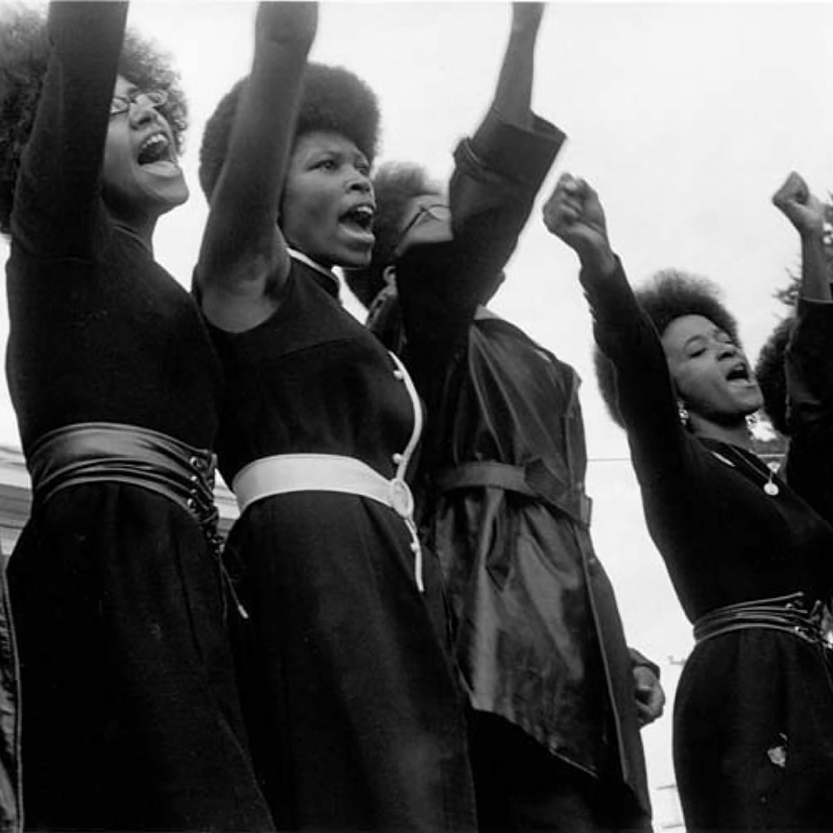 a group of women shouting with their right fists in the sky.