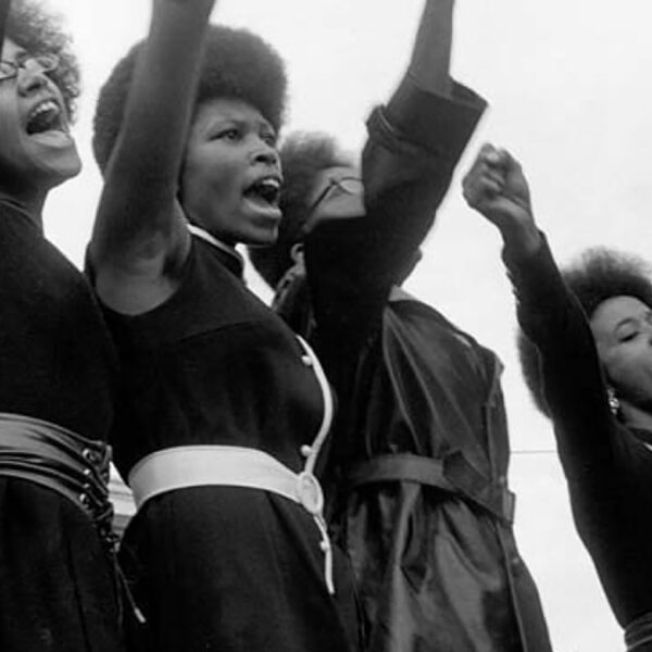 a group of women shouting with their right fists in the sky.