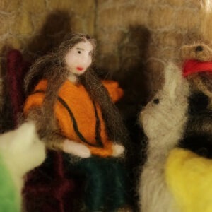 a woman doll made of wool sitting with animals made of wool.