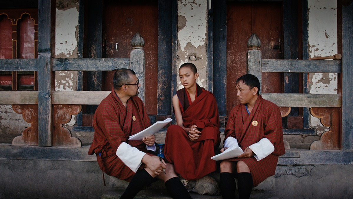 Three monks sitting outside a building.