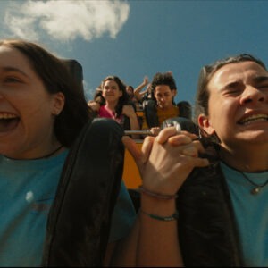 Two girls riding a roller coaster in blue shirts.