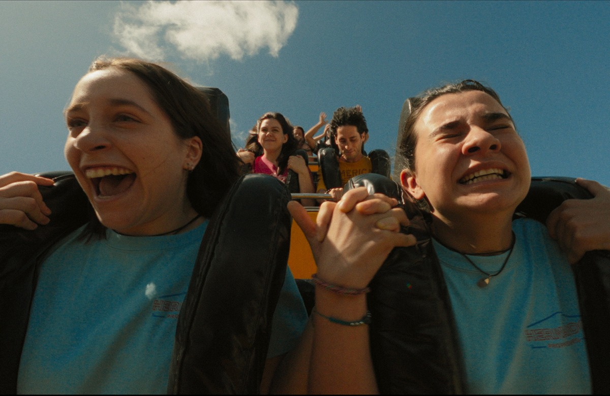 Two girls riding a roller coaster in blue shirts.