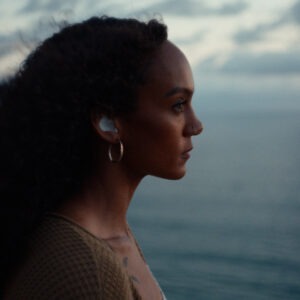 A woman with earbuds looking out to the ocean.