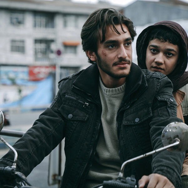 A man and a woman sitting on a motorcycle in a city.