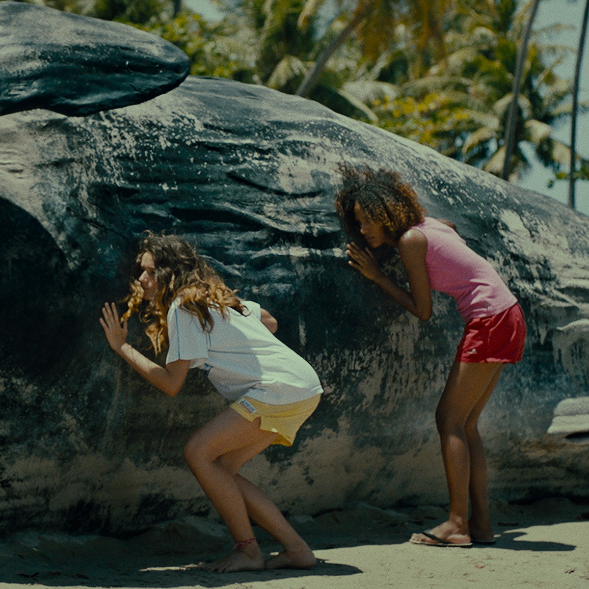Two girls are touching a large beached whale.