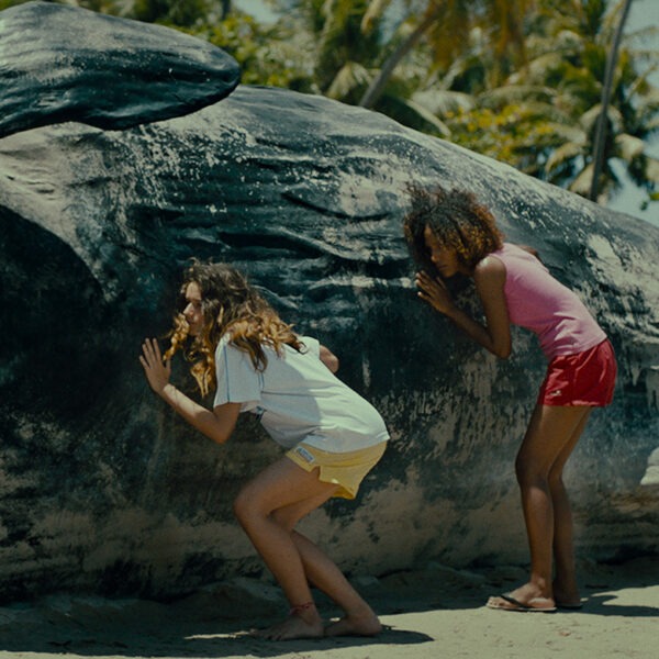 A group of children are touching a large beached whale.