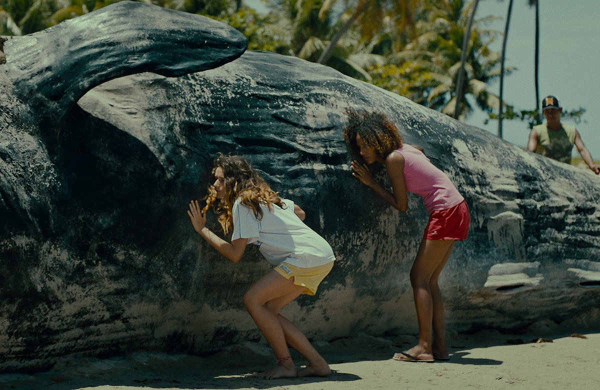 A group of children are touching a large beached whale.