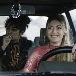 Two smiling women sitting in a car.
