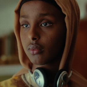 A young girl wearing hijab and headphones.