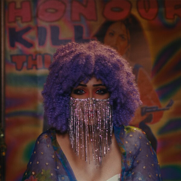 A woman with a purple wig in front of a store.