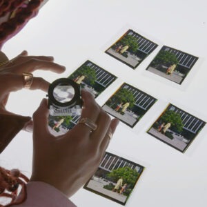A woman is looking at photos with a magnifying glass.