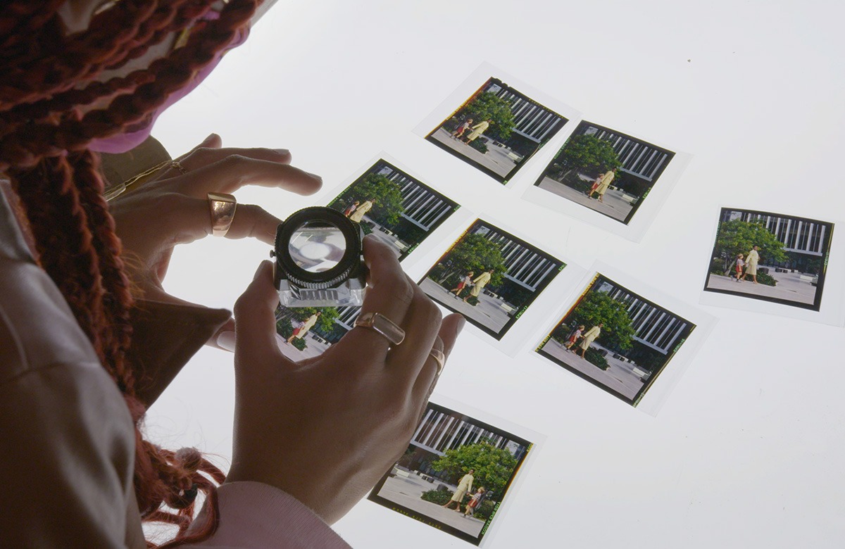 A woman is looking at photos with a magnifying glass.