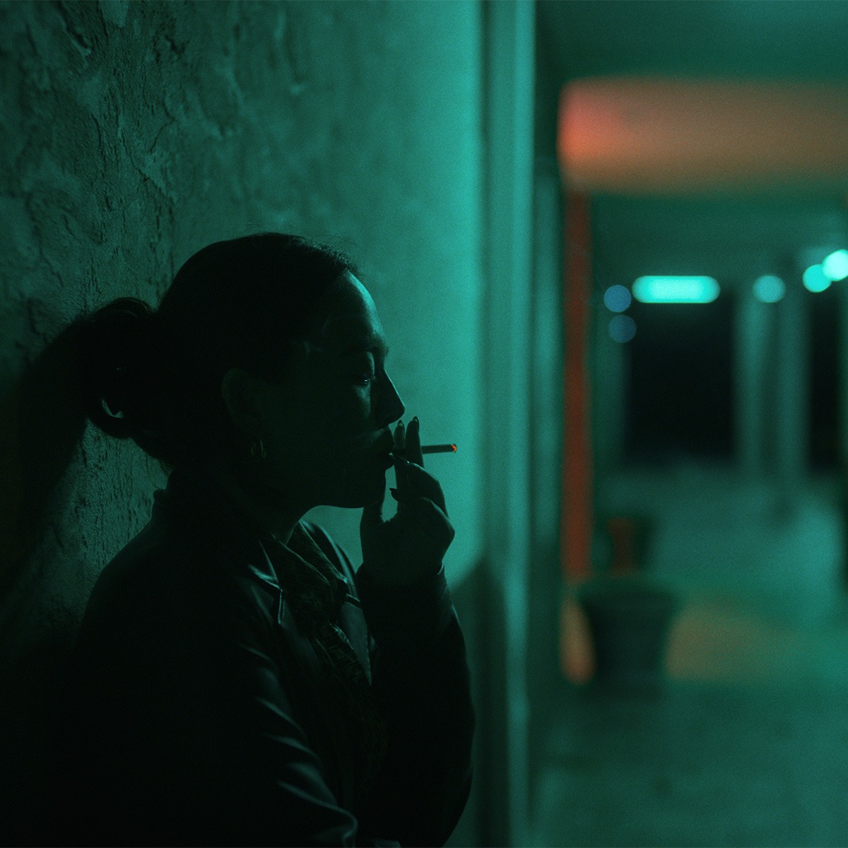 A woman smoking a cigarette at night.