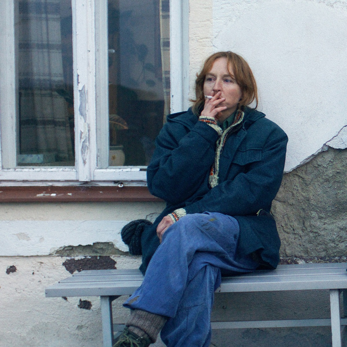 A woman sitting on a bench smoking a cigarette.